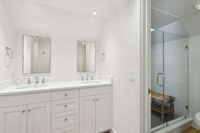 bathroom featuring vanity, toilet, a shower with door, and lofted ceiling