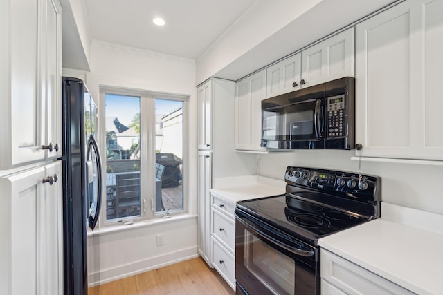 kitchen featuring black appliances, light hardwood / wood-style floors, white cabinetry, and crown molding