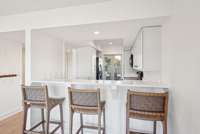 1505 Marsh Hvn, Johns Island, SC 29455 - kitchen featuring appliances with stainless steel finishes, white cabinets, a breakfast bar area, light wood-style floors, and baseboards