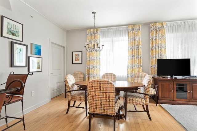 dining area featuring ornamental molding, an inviting chandelier, and light hardwood / wood-style flooring