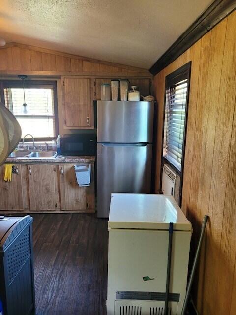 kitchen featuring wood walls, a textured ceiling, refrigerator, and stainless steel fridge