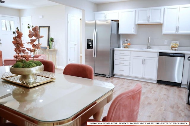 kitchen featuring sink, stainless steel appliances, light hardwood / wood-style floors, and white cabinets