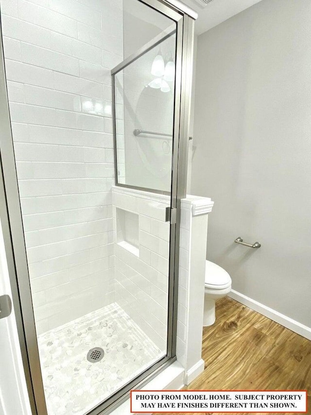 bathroom featuring an enclosed shower, wood-type flooring, and toilet