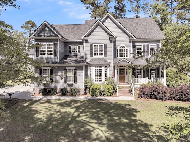 view of front of house featuring covered porch, a front lawn, and a shingled roof