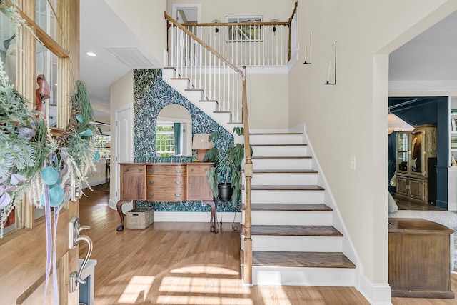 stairway featuring a high ceiling, wood finished floors, and baseboards