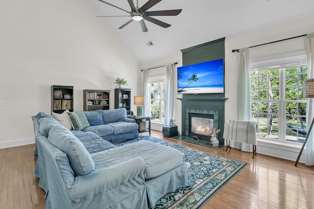 living area featuring ceiling fan, high vaulted ceiling, baseboards, a fireplace with flush hearth, and wood finished floors
