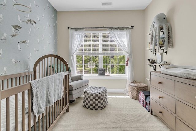 carpeted bedroom featuring a nursery area and baseboards