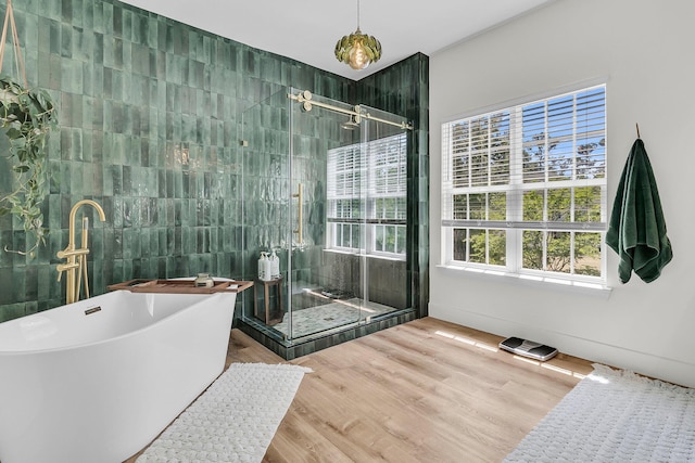 full bath featuring a stall shower, tile walls, a soaking tub, and wood finished floors