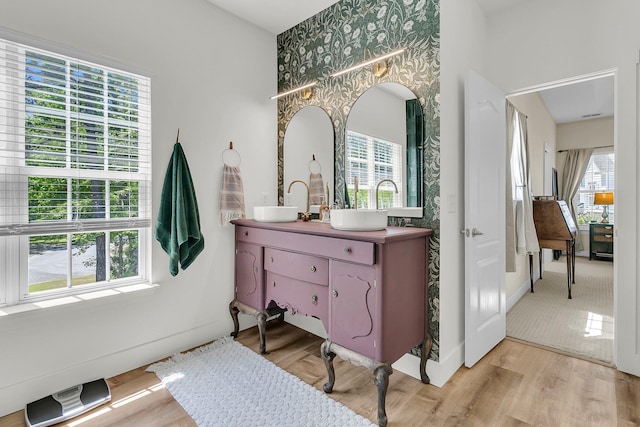bathroom with wallpapered walls, wood finished floors, vanity, and baseboards