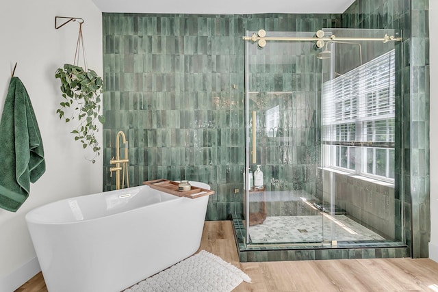 full bathroom with a shower stall, a freestanding bath, and wood finished floors