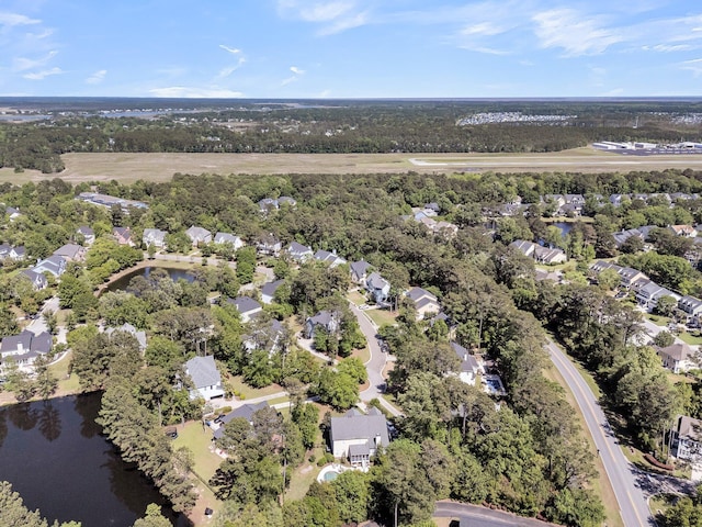 view of property location featuring nearby suburban area, a large body of water, and a tree filled landscape