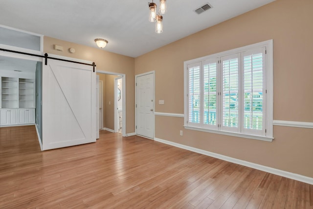 unfurnished bedroom featuring a barn door and light hardwood / wood-style flooring