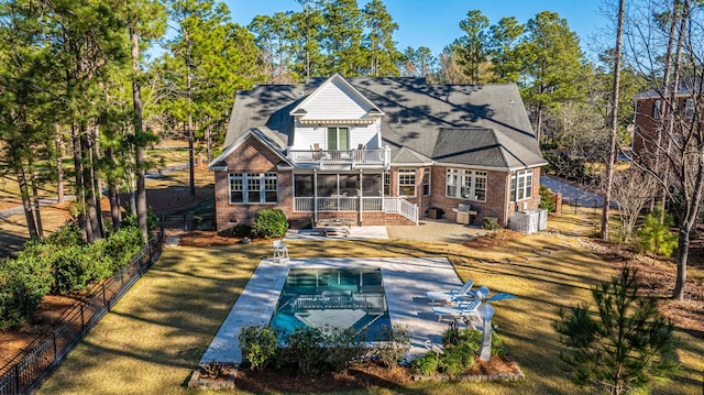 rear view of house with a patio, a balcony, and a sunroom