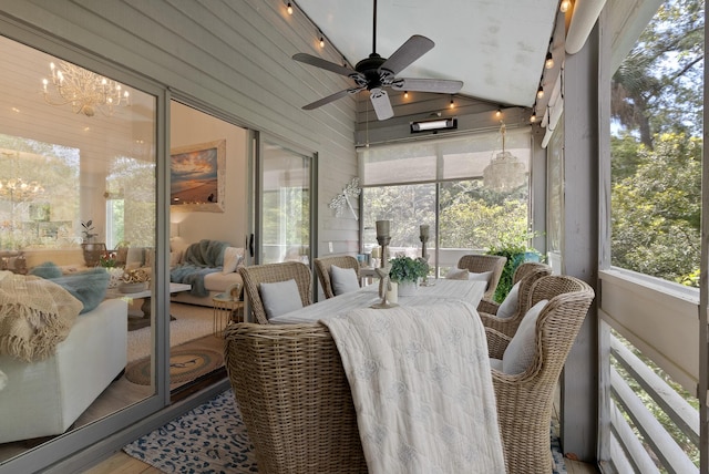 sunroom / solarium featuring ceiling fan with notable chandelier