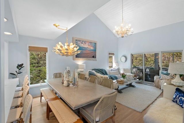 dining area with high vaulted ceiling, an inviting chandelier, and wood finished floors