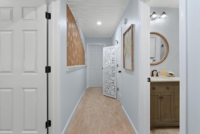 hallway featuring light colored carpet, a sink, and baseboards