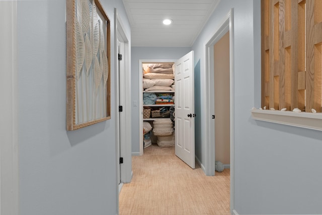 hallway featuring baseboards, recessed lighting, and light colored carpet