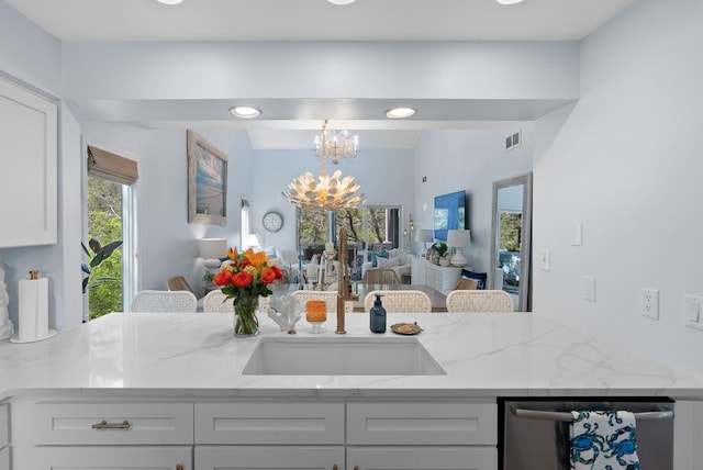 kitchen featuring stainless steel dishwasher, white cabinetry, visible vents, a chandelier, and open floor plan