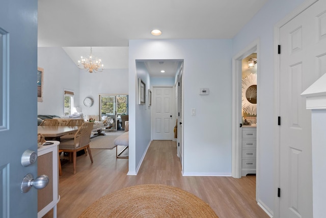 hallway featuring baseboards, light wood-type flooring, a notable chandelier, and recessed lighting
