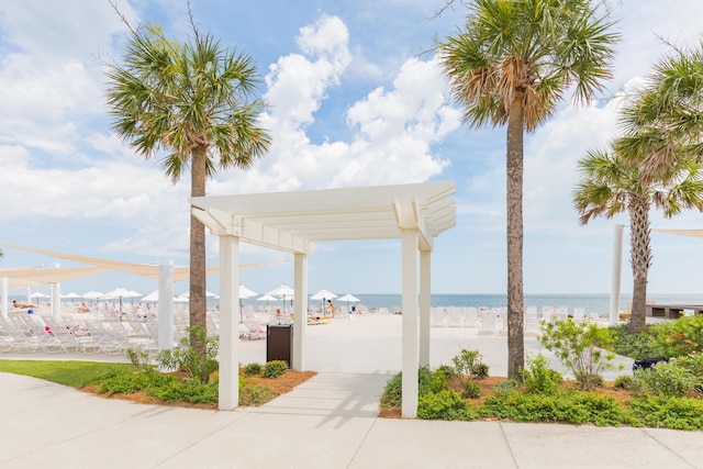 view of home's community featuring a water view, a view of the beach, and a pergola