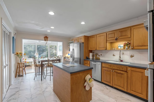 kitchen with sink, backsplash, crown molding, a kitchen island, and appliances with stainless steel finishes