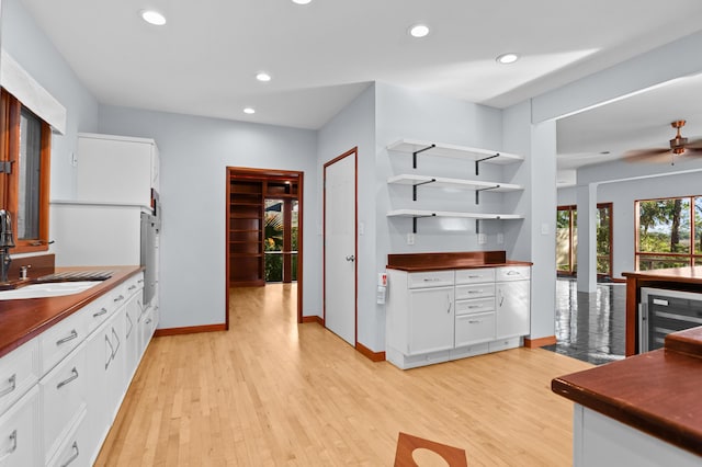 kitchen with sink, white cabinets, beverage cooler, and light wood-type flooring