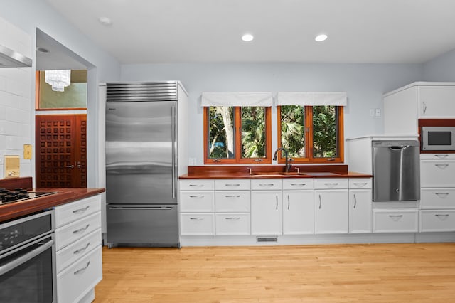 kitchen with appliances with stainless steel finishes, white cabinetry, and sink