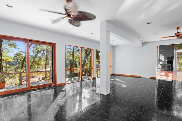 unfurnished living room featuring decorative columns and ceiling fan