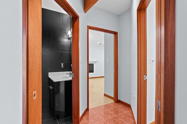 hall featuring beamed ceiling, light tile patterned floors, and sink