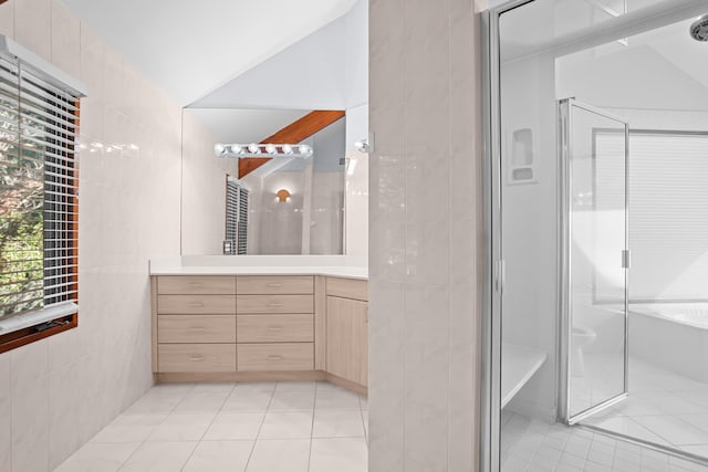 bathroom featuring an enclosed shower, vanity, vaulted ceiling, tile walls, and tile patterned flooring