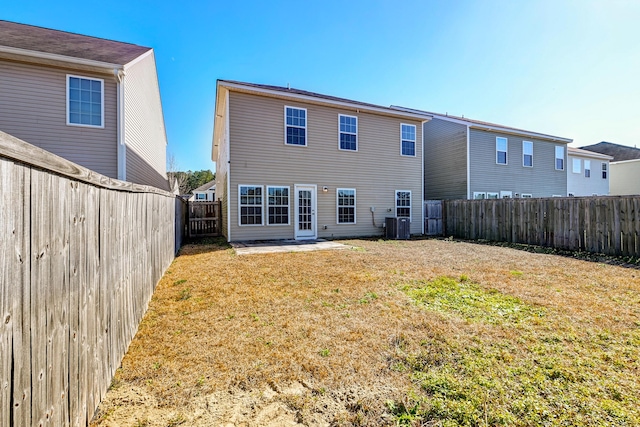 rear view of house with central AC unit and a lawn