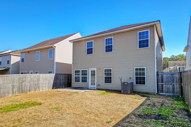 back of property with a lawn, central air condition unit, and a patio area