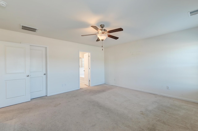 unfurnished bedroom with connected bathroom, light colored carpet, and ceiling fan