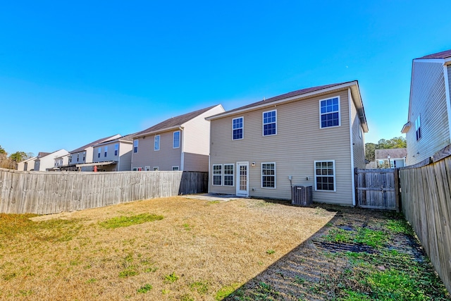 rear view of house featuring cooling unit and a lawn