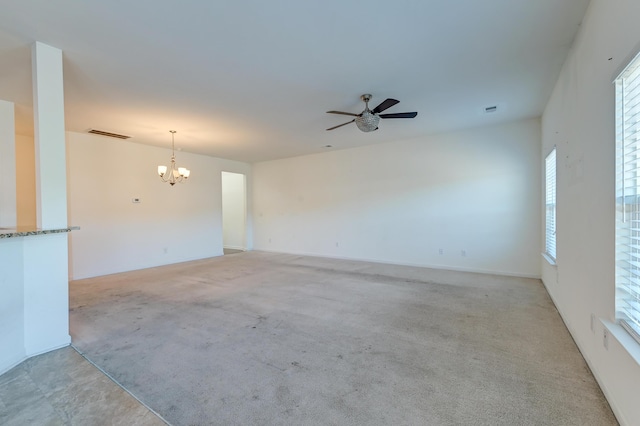 carpeted spare room with ceiling fan with notable chandelier