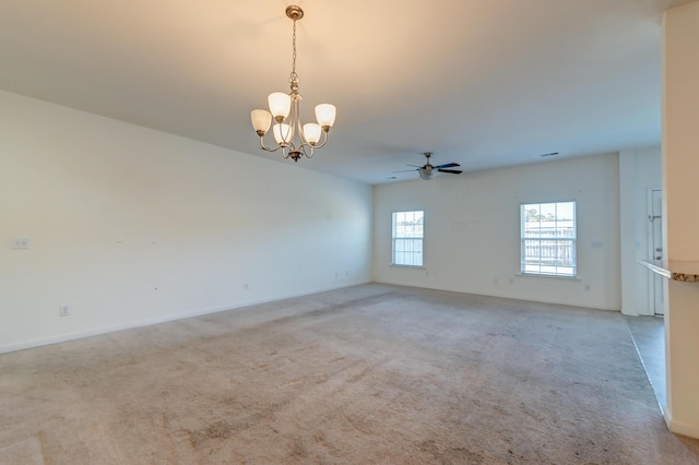 carpeted spare room featuring ceiling fan with notable chandelier