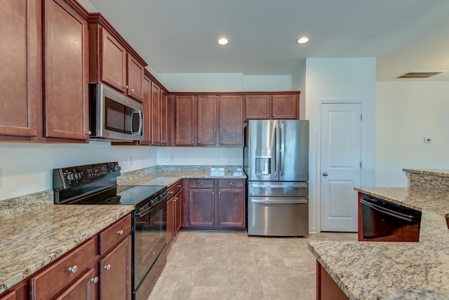 kitchen with light stone countertops and black appliances