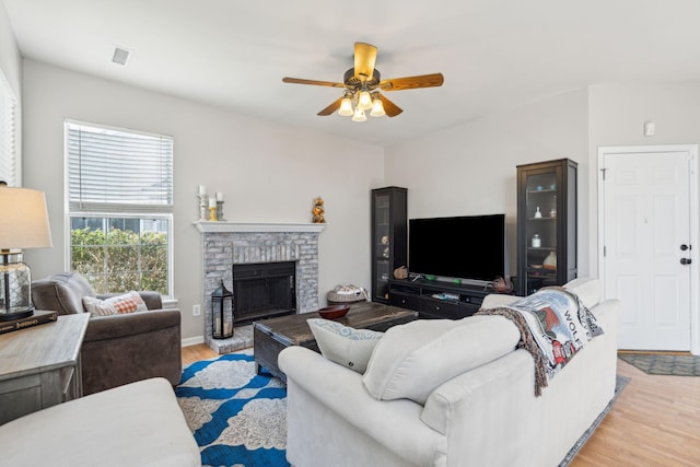 living room featuring a fireplace, light hardwood / wood-style flooring, and ceiling fan