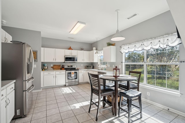 kitchen with appliances with stainless steel finishes, decorative light fixtures, white cabinetry, sink, and light tile patterned floors