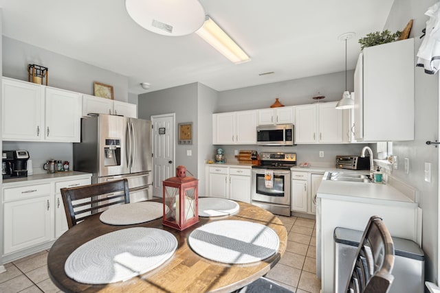 kitchen with sink, white cabinetry, decorative light fixtures, light tile patterned floors, and appliances with stainless steel finishes