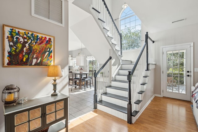 stairs with hardwood / wood-style flooring and a towering ceiling