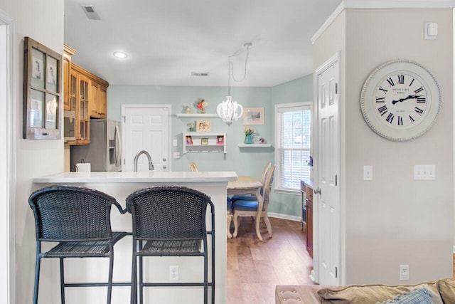 kitchen featuring a peninsula, visible vents, light wood-style floors, stainless steel fridge with ice dispenser, and glass insert cabinets