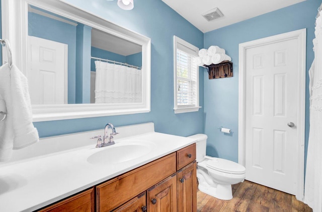 full bathroom with visible vents, vanity, toilet, and wood finished floors