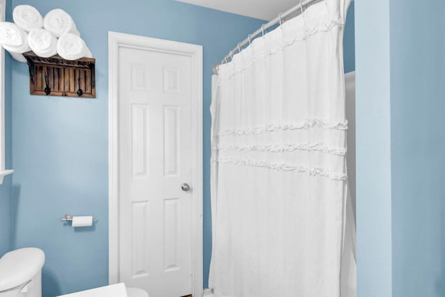 bathroom with a shower with shower curtain and toilet