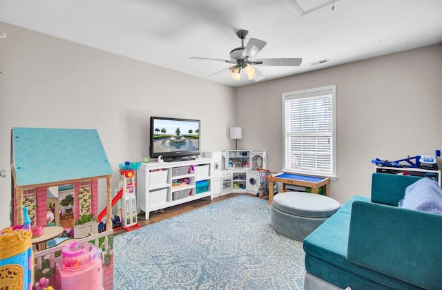 playroom featuring a ceiling fan, attic access, visible vents, and wood finished floors