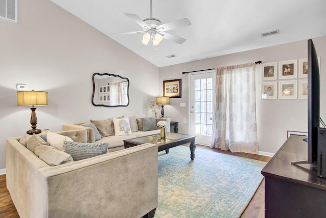 living room with lofted ceiling, a ceiling fan, visible vents, and wood finished floors