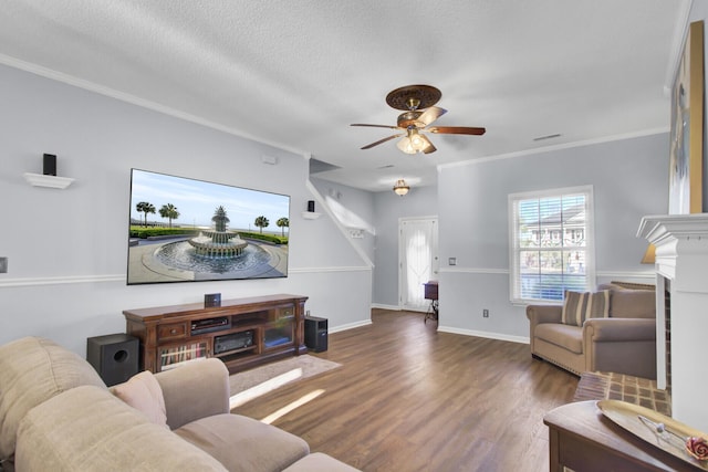 living room with a brick fireplace, ceiling fan, dark hardwood / wood-style floors, ornamental molding, and a textured ceiling