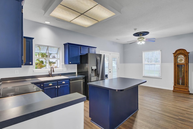 kitchen with a wealth of natural light, stainless steel appliances, ceiling fan, sink, and blue cabinetry