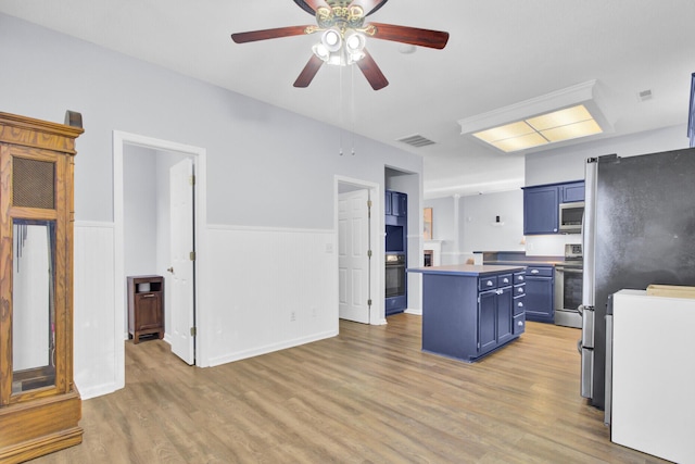 kitchen featuring blue cabinetry, ceiling fan, wood-type flooring, a kitchen island, and appliances with stainless steel finishes