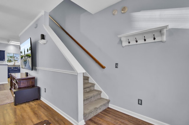 staircase with hardwood / wood-style floors and ornamental molding